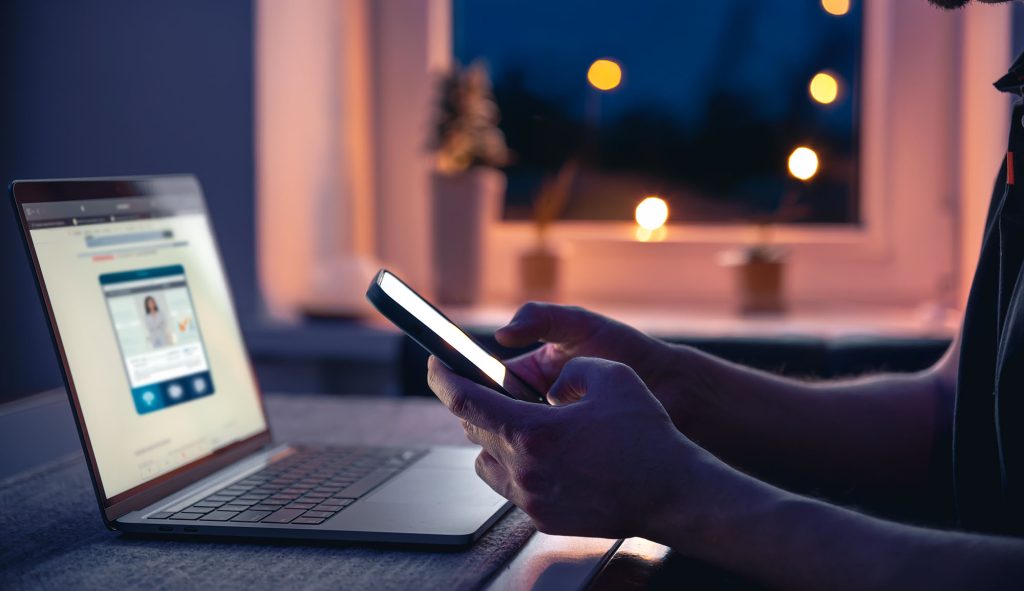 Someone comparing options on a laptop and phone late in the evening